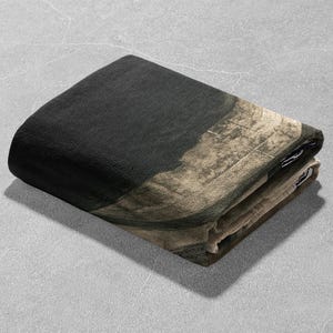 May include: A folded black and beige throw blanket with a textured pattern.
