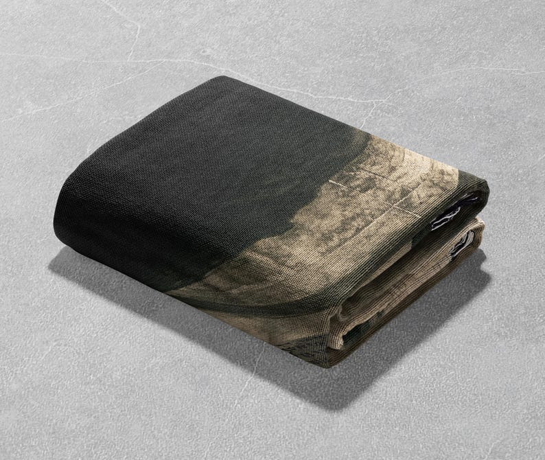 May include: A folded black and beige throw blanket with a textured pattern.