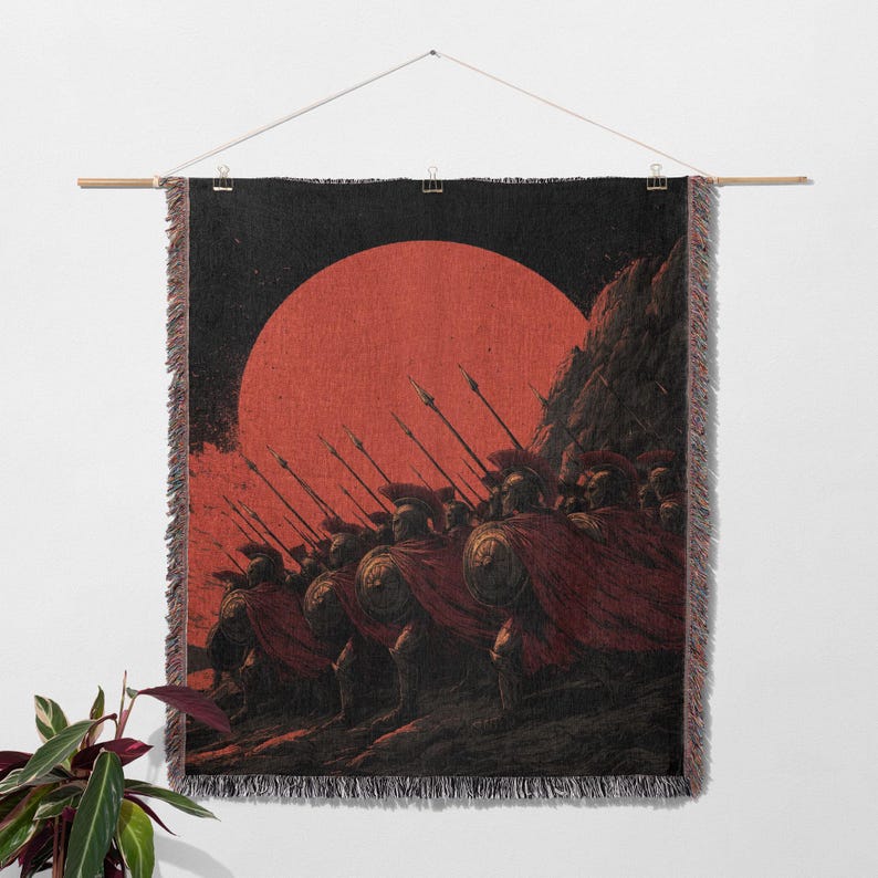 May include: A woven wall tapestry depicting a line of ancient warriors in red capes and helmets, holding spears. A large red sun is in the background. The tapestry is hung from a wooden rod.