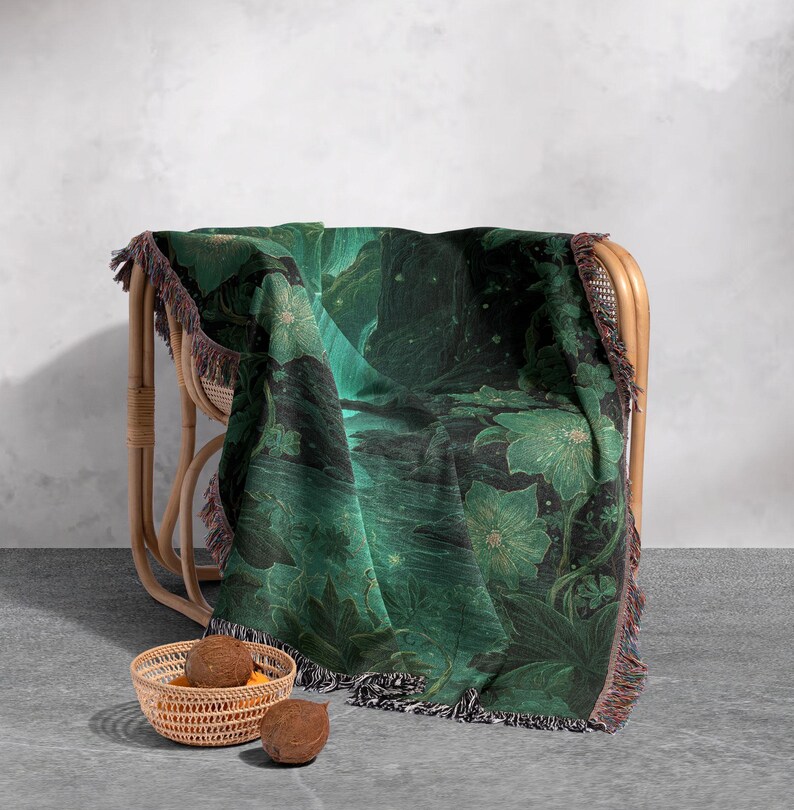May include: A green and black floral throw blanket draped over a wicker chair. The blanket features a botanical design with large flowers and foliage. The blanket has a fringed edge and is approximately 60 inches by 50 inches.
