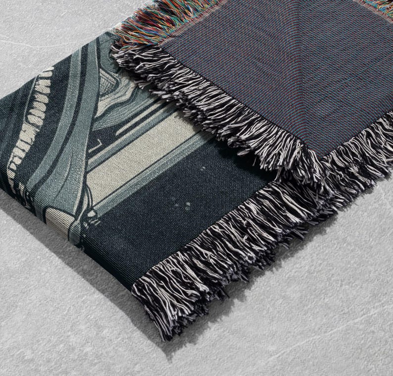 May include: A black and white woven throw blanket with a geometric pattern. The blanket has a fringe border.