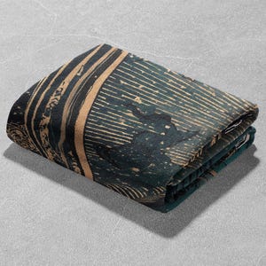 May include: Folded textile with a dark teal and tan pattern. The design features vertical and horizontal lines, with a textured appearance. The fabric is folded neatly, showcasing the intricate details of the print. The overall aesthetic is modern and artistic.