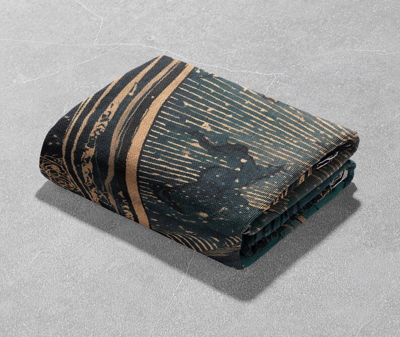 May include: Folded textile with a dark teal and tan pattern. The design features vertical and horizontal lines, with a textured appearance. The fabric is folded neatly, showcasing the intricate details of the print. The overall aesthetic is modern and artistic.
