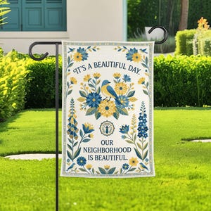 May include: A rectangular garden flag featuring a cream background with a central blue bird surrounded by yellow and blue floral patterns. The text reads IT'S A BEAUTIFUL DAY. OUR NEIGHBORHOOD IS BEAUTIFUL. A small circular emblem with a necktie is centered.