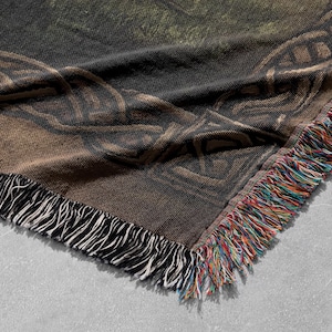 K&ouml;nnte beinhalten: Eine braune und schwarze gewebte Wolldecke mit einem keltischen Knotendesign und Fransen an den R&auml;ndern.