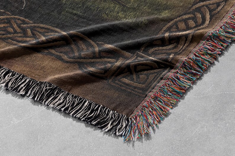 K&ouml;nnte beinhalten: Eine braune und schwarze gewebte Wolldecke mit einem keltischen Knotendesign und Fransen an den R&auml;ndern.