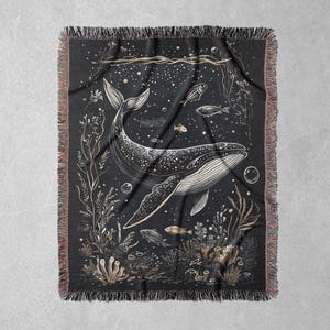 May include: A black woven tapestry with a white outline of a whale swimming through a field of seaweed and bubbles. The whale is surrounded by small fish and other sea life.
