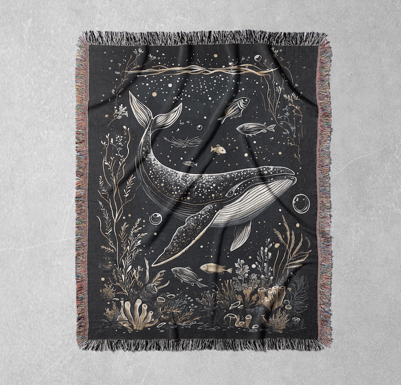 May include: A black woven tapestry with a white outline of a whale swimming through a field of seaweed and bubbles. The whale is surrounded by small fish and other sea life.