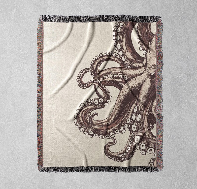 May include: A woven throw blanket featuring a brown and white octopus design. The octopus is drawn in a detailed style with many tentacles.