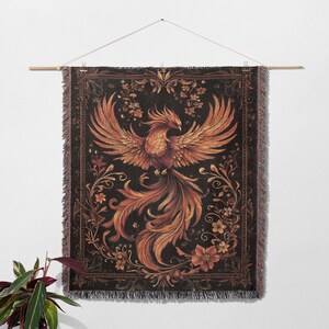 May include: A tapestry wall hanging with a black background and a detailed illustration of a phoenix with orange and yellow feathers. The phoenix is surrounded by intricate floral designs in shades of brown, orange, and yellow.
