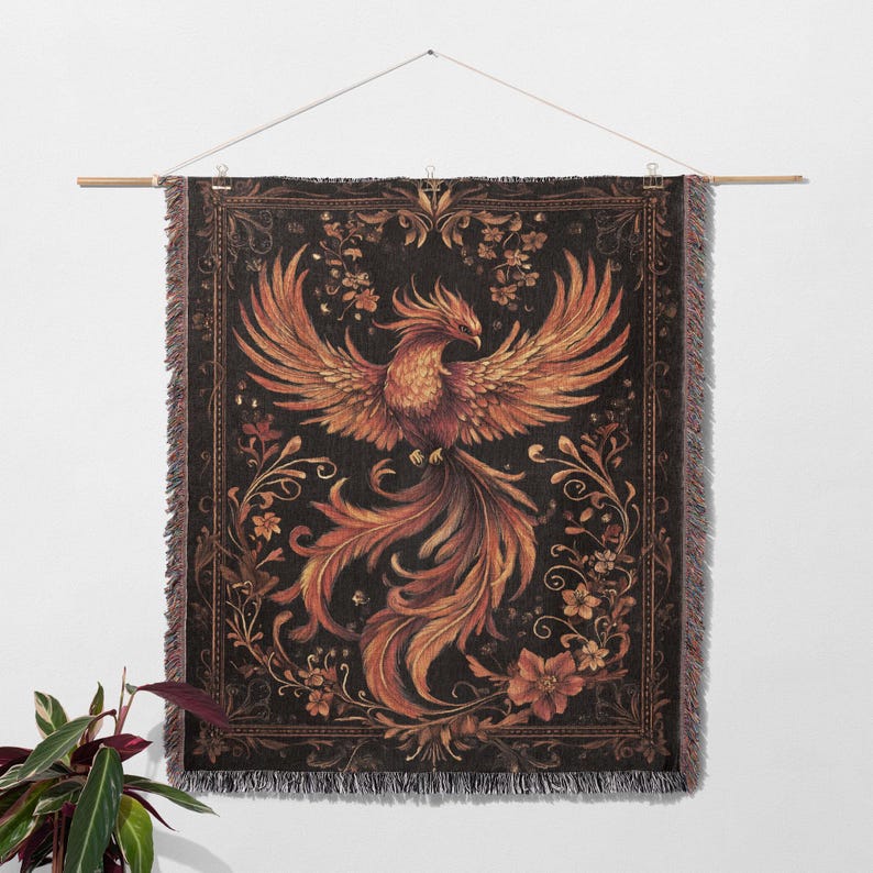 May include: A tapestry wall hanging with a black background and a detailed illustration of a phoenix with orange and yellow feathers. The phoenix is surrounded by intricate floral designs in shades of brown, orange, and yellow.