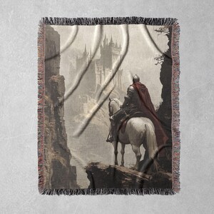 May include: A tapestry featuring a knight on horseback riding towards a large, imposing castle in the distance. The knight is wearing a red cloak and a helmet, and the horse is white. The background is a misty, gray landscape.
