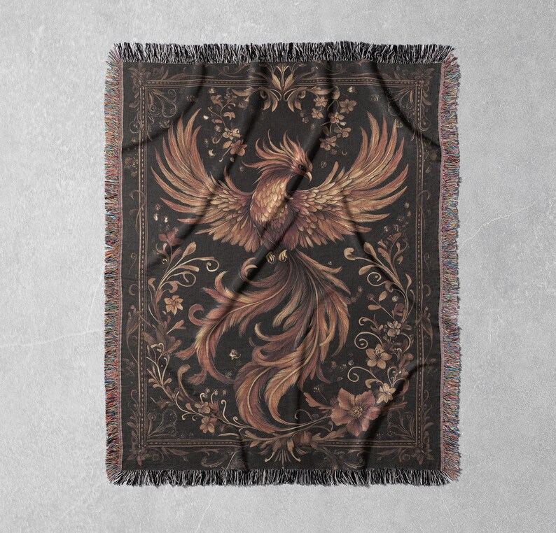 May include: A woven tapestry throw blanket featuring a gold phoenix with intricate details against a dark background. The phoenix is surrounded by floral designs and a decorative border.