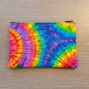 May include: A small zippered pouch with a tie-dye pattern in shades of blue, green, yellow, orange, pink, and red.