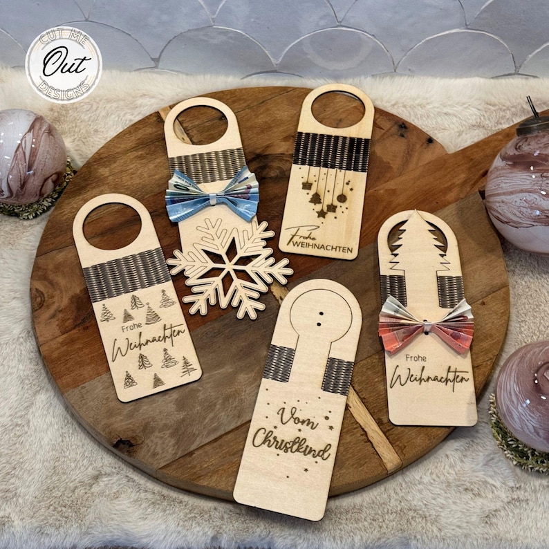 May include: Five wooden door hangers with a Christmas theme. Each hanger has a different design, including a snowflake, a Christmas tree, a bow, and the words "Frohe Weihnachten" and "Vom Christkind".