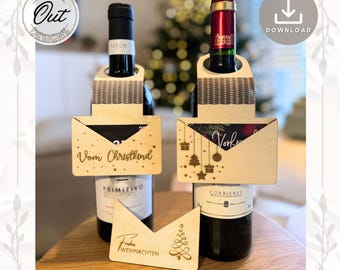 May include: Two wooden wine bottle holders with a gift card slot shaped like an envelope. The holders are decorated with Christmas-themed designs and the text "Vom Christkind" and "Vorfreude".