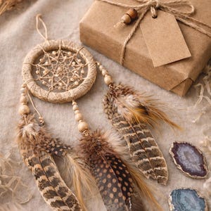 May include: A handcrafted dreamcatcher with brown feathers and wooden beads, alongside a wrapped gift box tied with twine and a blank tag. Two polished agate stones in shades of purple and blue add a touch of natural beauty.