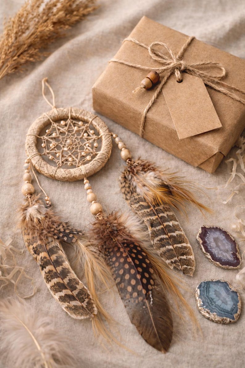 May include: A handcrafted dreamcatcher with brown feathers and wooden beads, alongside a wrapped gift box tied with twine and a blank tag. Two polished agate stones in shades of purple and blue add a touch of natural beauty.