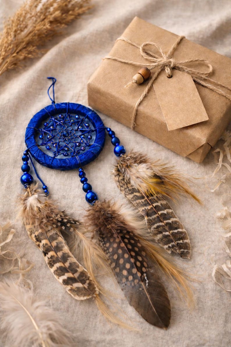 May include: A handcrafted blue dreamcatcher with beaded accents and natural feathers. A wrapped gift box with a tag is also present. The dreamcatcher is a decorative item, often used for home decor.