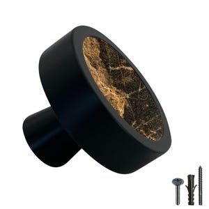 Può includere: Pomo per armadio nero con una faccia rotonda in marmo dorato e nero. Il pomo ha una base nera e una vite per l'installazione.