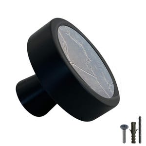 Peut inclure: Bouton de porte noir avec une face ronde gris argenté à motif craquelé. Le bouton a une base noire et est livré avec des vis.