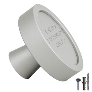 Peut inclure: Cadre photo en métal argenté avec une ouverture ronde et une base. Le cadre porte la mention "DEIN DESIGN BILD" gravée sur le devant.