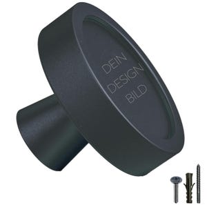 Peut inclure: Bouton noir ovale avec un bord surélevé et une base plate. Le bouton porte la gravure "DEIN DESIGN BILD" sur le devant.