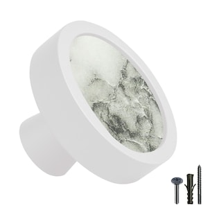 Op de afbeelding: Witte keramische kastknop met een rond, grijs en wit marmerpatroon. De knop heeft een kleine, ronde basis.