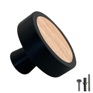 Peut inclure: Bouton de porte rond noir avec un insert en bois. Le bouton a une base noire et un dessus rond avec un insert en bois. Le bouton est fixé sur un fond blanc.