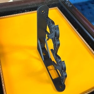 May include: Black metal shelf bracket with a decorative design of three birds in flight. The bracket is mounted on a yellow surface.
