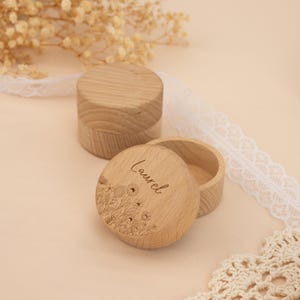 May include: Two round wooden boxes with lids. The top of one box has a floral design and the name "Laurel" engraved on it.