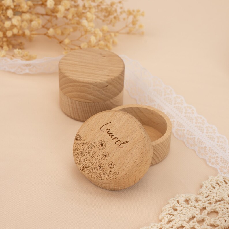 May include: Two round wooden boxes with lids. The top of one box has a floral design and the name "Laurel" engraved on it.