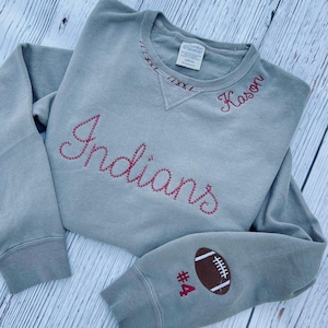 May include: Gray sweatshirt with red embroidered text "Indians" and "Kason" on the front. The left sleeve has a red number "4" and a brown football.