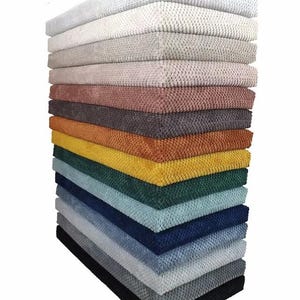 May include: A vertical stack of rectangular fabric swatches featuring a textured, raised honeycomb pattern. The collection includes a variety of colors ranging from white, cream, and beige to pink, orange, yellow, green, blue, gray, and black.