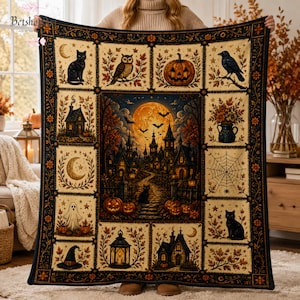 Peut inclure: Un plaid rectangulaire présentant une scène centrale de village gothique sous une pleine lune avec des chauves-souris, entouré d'une grille de panneaux illustrant des chats noirs, des hiboux, des citrouilles, un fantôme et une toile d'araignée.