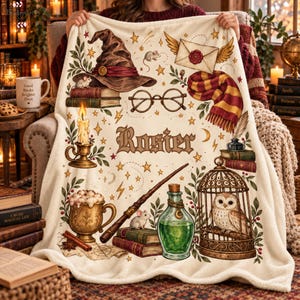 May include: A cream-colored fleece blanket featuring a central name Rosier surrounded by illustrations of a wizard hat, books, a winged envelope, glasses, a striped scarf, a candle, a mug, a wand, a potion bottle, and an owl in a birdcage.