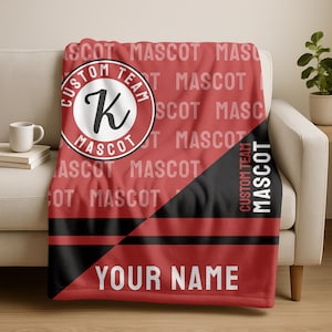 May include: A red and black custom team mascot blanket. The blanket has a circular emblem with a letter "K" and the words "Custom Team Mascot". The blanket also has the words "Your Name" printed on it.