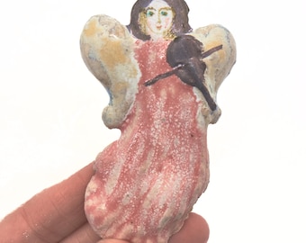 金色の光輪とバイオリン、そしてミニチュアの天使の手描きの顔が付いた小さな陶器の天使。