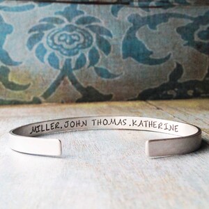May include: A silver bangle bracelet with the inscription "MILLER. JOHN. THOMAS. KATHERINE" engraved on the outside.