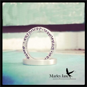 Puede incluir: Dos anillos de plata con las palabras "now" y "forever" grabadas. Los anillos están apilados uno encima del otro.
