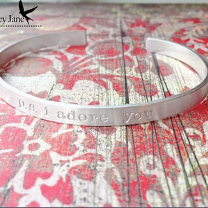 May include: Silver bangle bracelet with the inscription "p.s. i adore you".