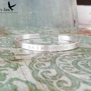 May include: Silver bangle bracelet with the inscription "P.S. I adore you".