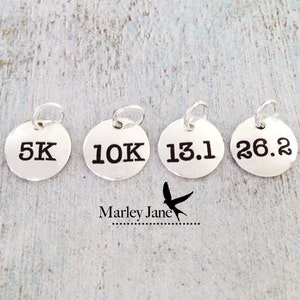 May include: Four silver charms with black lettering, reading "5K", "10K", "13.1", and "26.2".