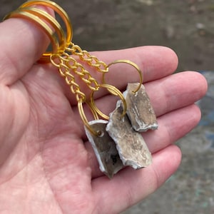 May include: A set of three ceramic mugs with a speckled, matte finish. The mugs are in shades of cream, light gray, and dark gray. Each mug has a simple, minimalist design, perfect for coffee or tea.