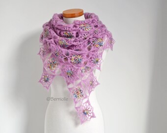 May include: A delicate lavender crochet shawl with a lacy pattern and colourful accents. The shawl is draped over a white mannequin.