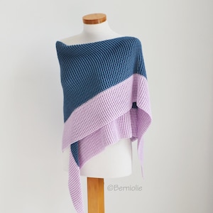 May include: A blue and lavender knitted shawl draped over a mannequin. The shawl is divided diagonally, with blue on top and lavender on the bottom. The knitted texture is visible, and the shawl is designed to be worn over the shoulders.