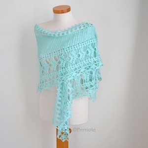 Könnte beinhalten: Ein hellblauer Häkel-Schal mit einem zarten Spitzenmuster. Der Schal ist über eine Schaufensterpuppe gelegt.