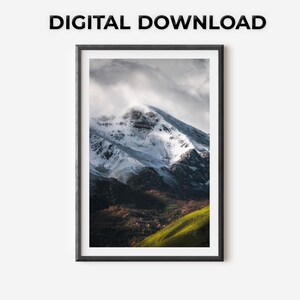 Può includere: Una stampa incorniciata di un paesaggio montano con una cima innevata e un cielo nuvoloso. L'immagine include una collina verde e il testo "DIGITAL DOWNLOAD" in alto. La cornice è nera.