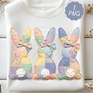 Op de afbeelding: Witte sweatshirt met drie patchwork konijn ontwerpen. Elk konijn heeft een ander patroon, waaronder bloemen, stippen en ruitjes, met pastelkleuren en een strik. Het ontwerp bevat een witte pomponstaart en is gelabeld met "1 PNG".