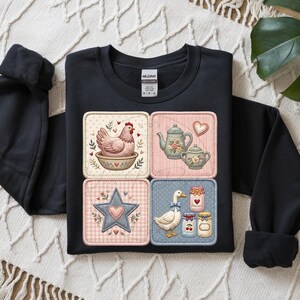 Puede incluir: Sudadera negra con cuatro parches cuadrados con ilustraciones de tem&aacute;tica campestre. Los parches representan una gallina en un cuenco, teteras, una estrella con un coraz&oacute;n y un ganso con tarros de mermelada. Cuello redondo, mangas largas.